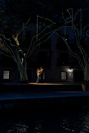 Trees decorated with string lights illuminate a dark outdoor space creating a magical nighttime atmosphere.