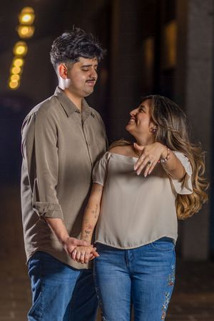 Romantic couple in casual attire sharing intimate moments against a backdrop of twinkling lights at night.
