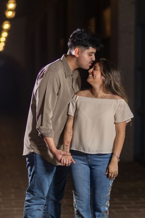 A romantic couple in casual attire sharing tender moments together in a dimly lit setting.
