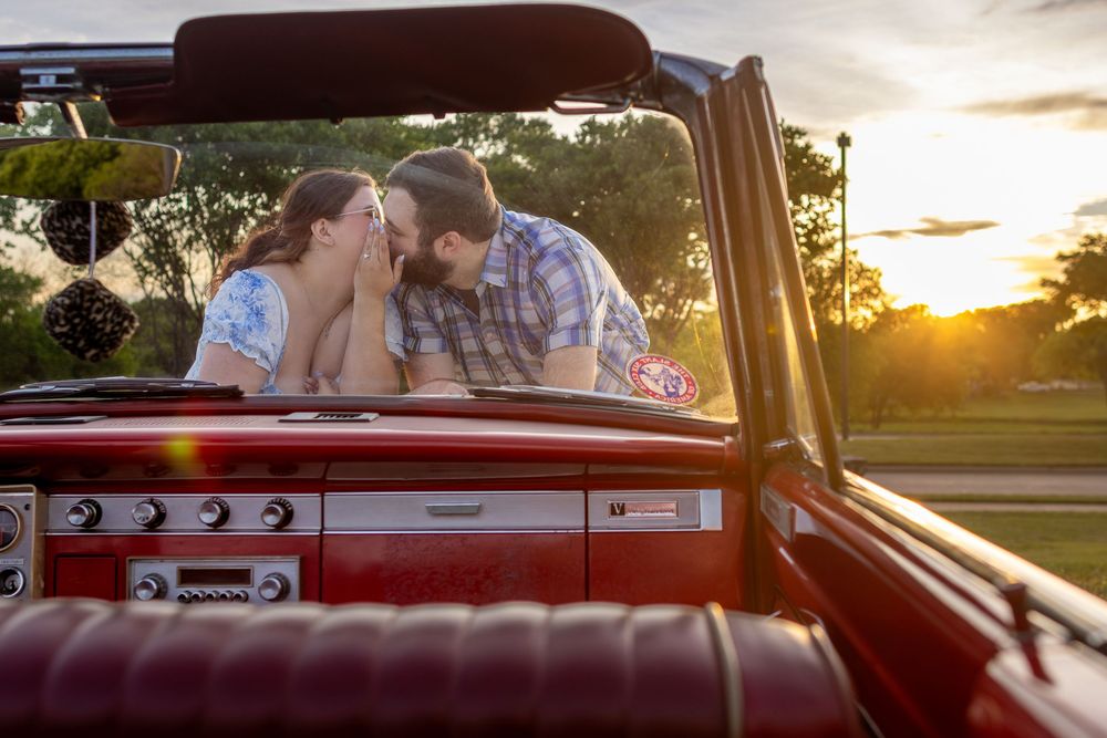 Romantic couple sharing a tender moment in a vintage red convertible car at golden sunset.