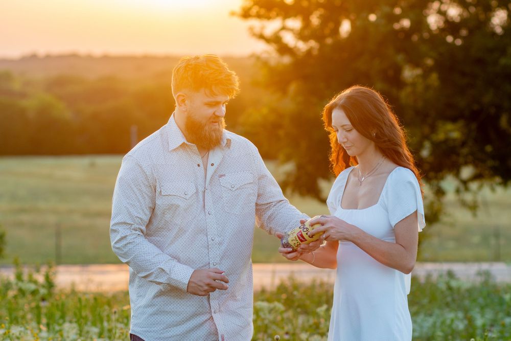 Couple walking through blooming field at sunset wearing white clothing.