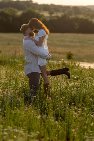A couple embracing in a golden sunset meadow filled with wildflowers.