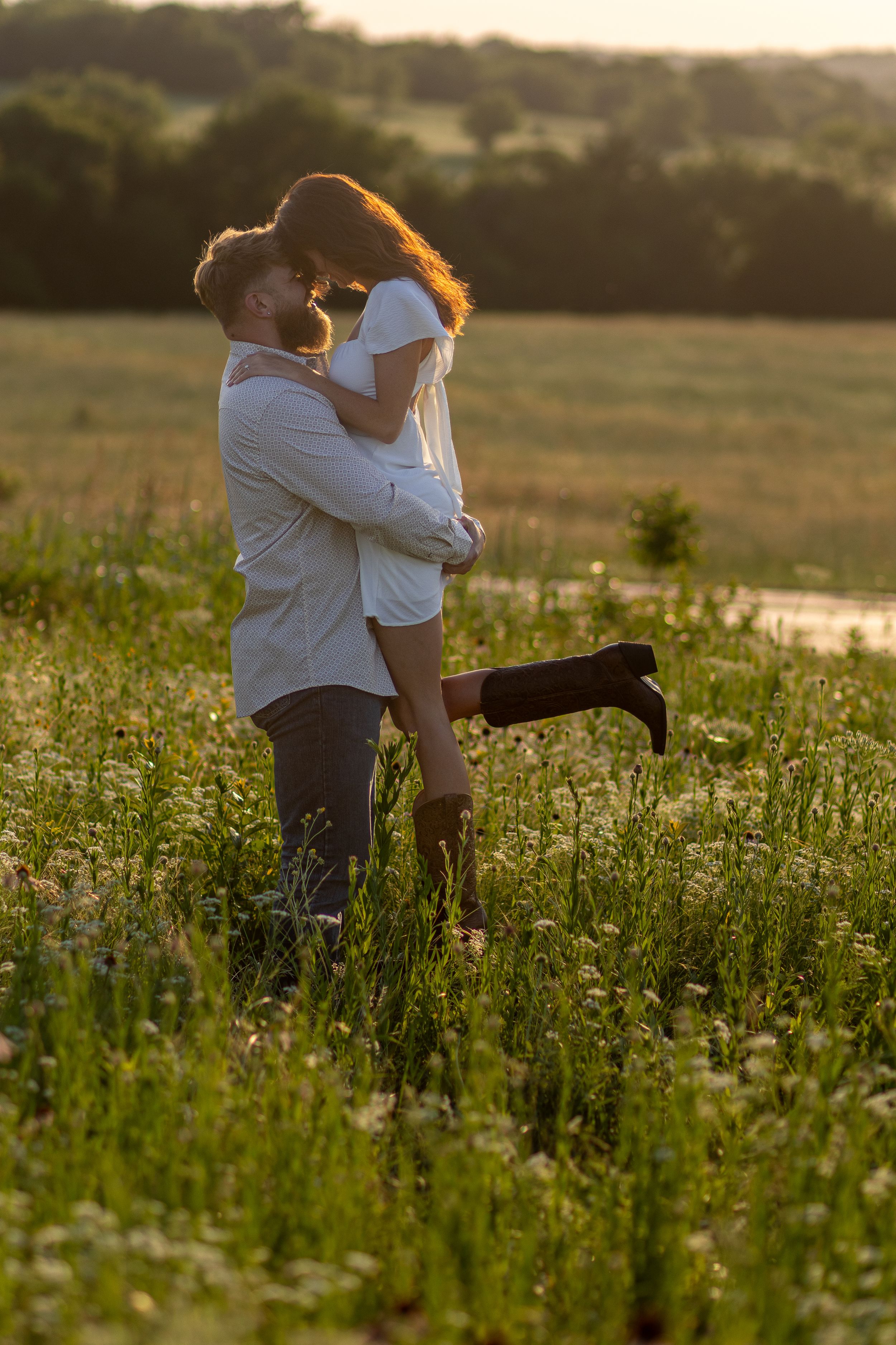 A couple embracing in a golden sunset meadow filled with wildflowers.