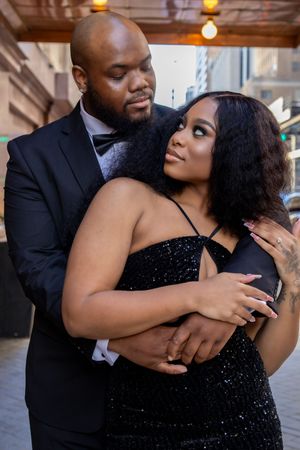 Romantic couple in formal attire embrace and share intimate moments during an urban photo session.