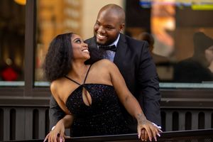 A romantic couple shares an intimate moment on an outdoor balcony during an evening photoshoot.