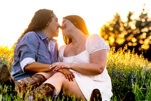 Couple sitting intimately in a wildflower field during golden hour sunset.