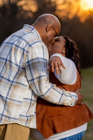 A series of tender embraces between two people at sunset wearing a plaid shirt and brown sweater against a golden backdrop.