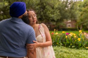 Couple sharing a romantic moment in a colorful garden, man in blue turban embracing woman in floral dress.