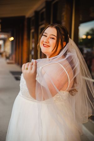 A bride in a flowing white gown twirls playfully with her veil.