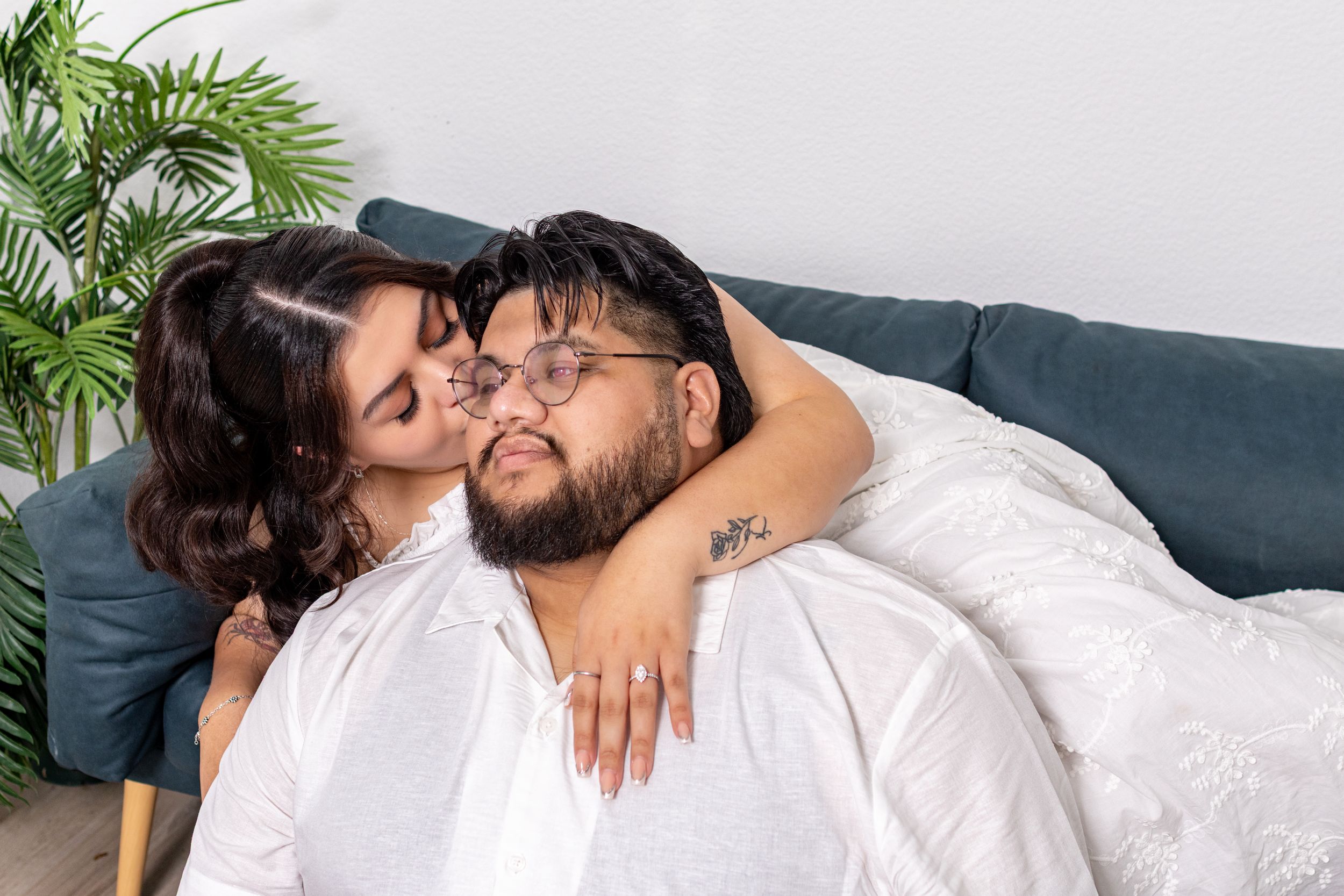 A couple sharing a tender moment, woman kissing man on cheek while embracing on a cozy couch.