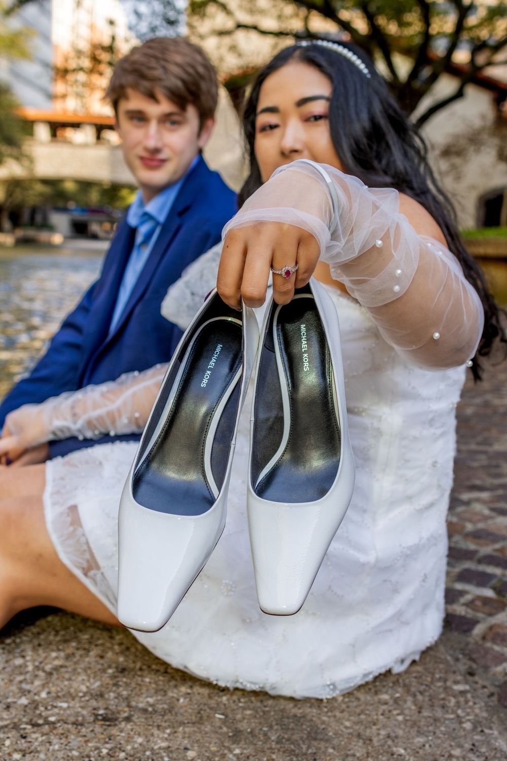 White bridal shoes being carefully wrapped in protective tissue paper during a wedding preparation photoshoot.