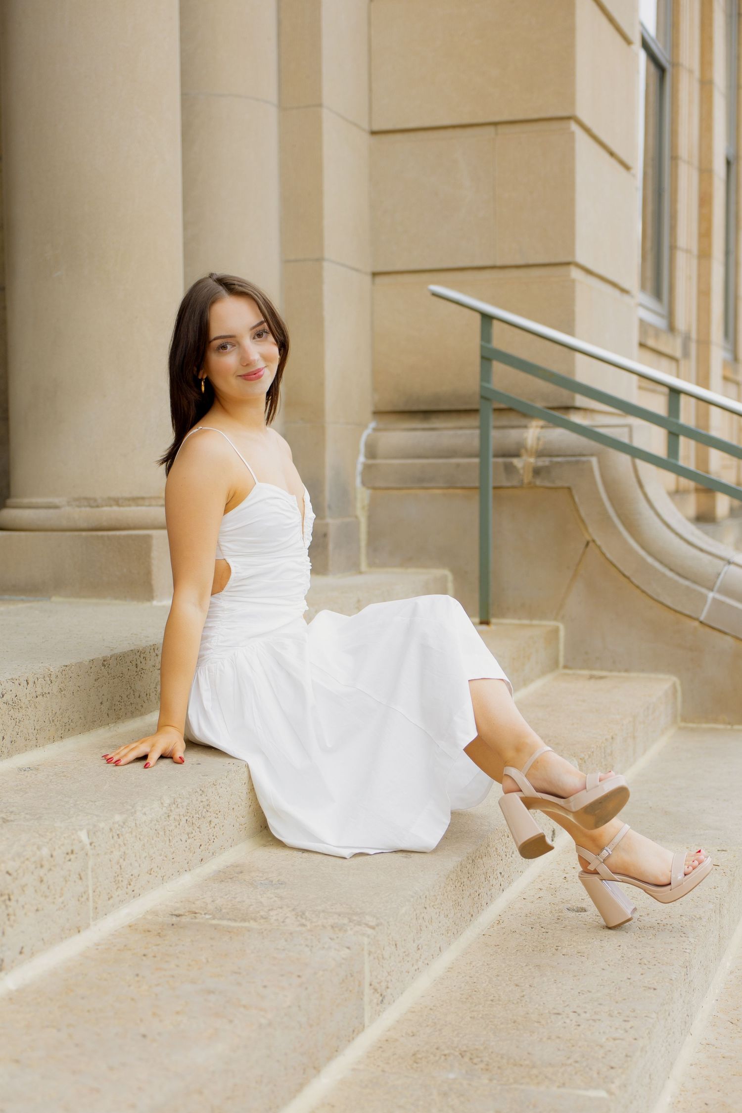 Senior girl in a blue dress leaning against a trellis with greenery in the background
