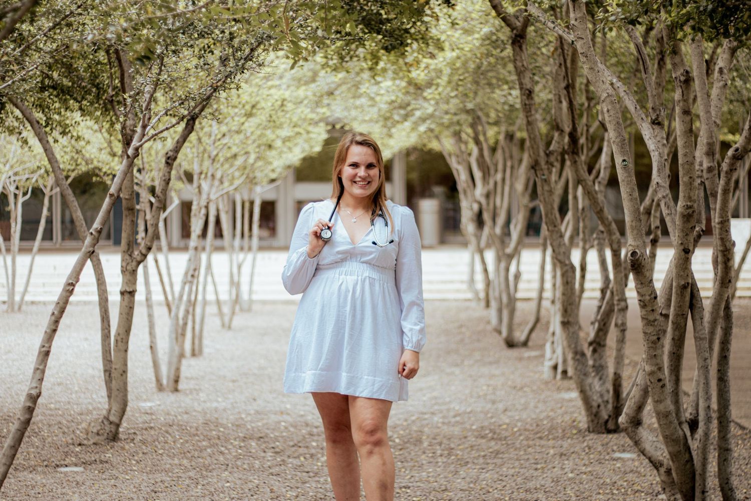 Light blue dress and flowy hair as someone walks along a path lined with trees in a dreamy garden setting.