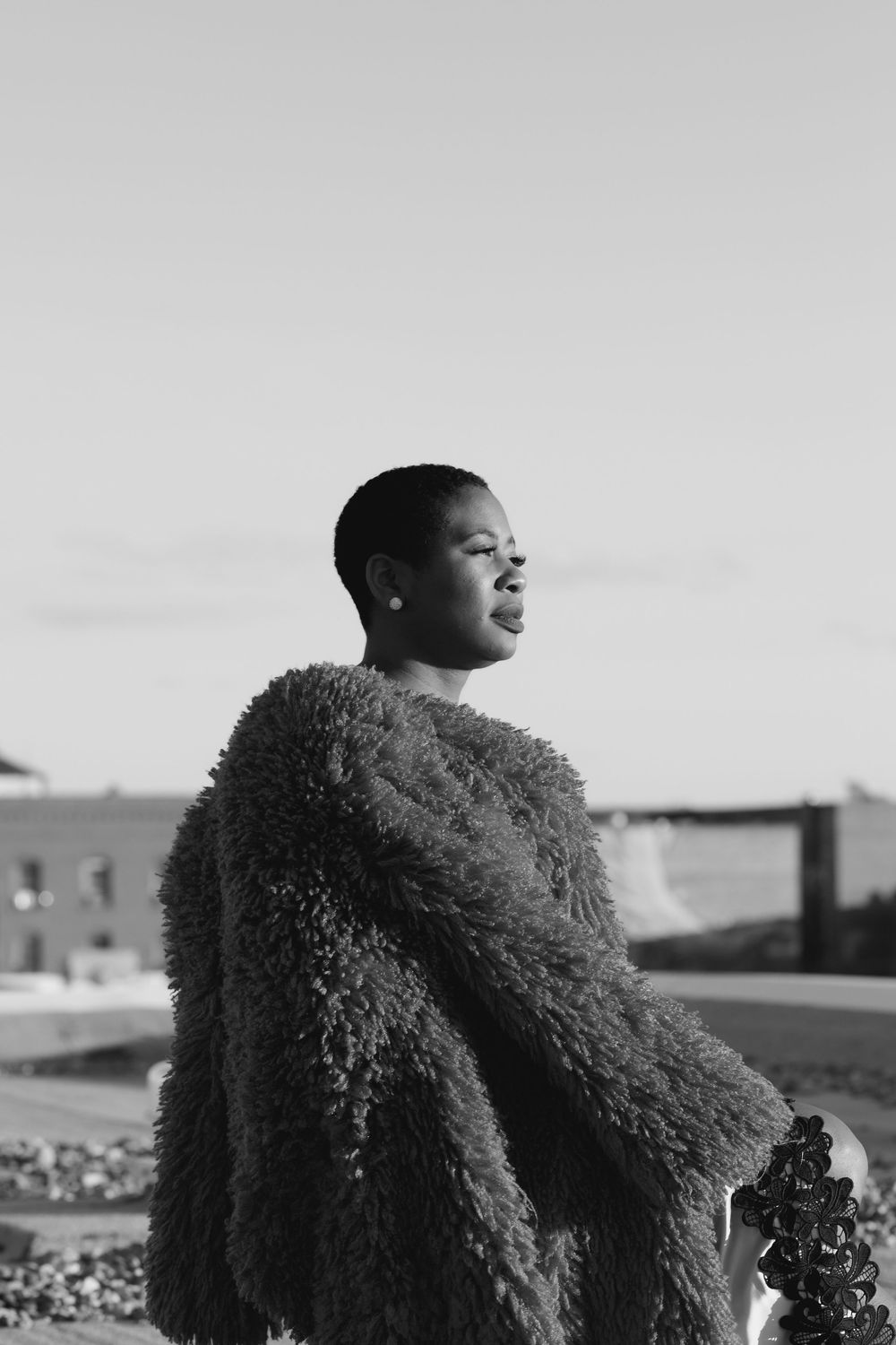 Fashion portrait featuring a textured black fur coat against a minimalist grey background.