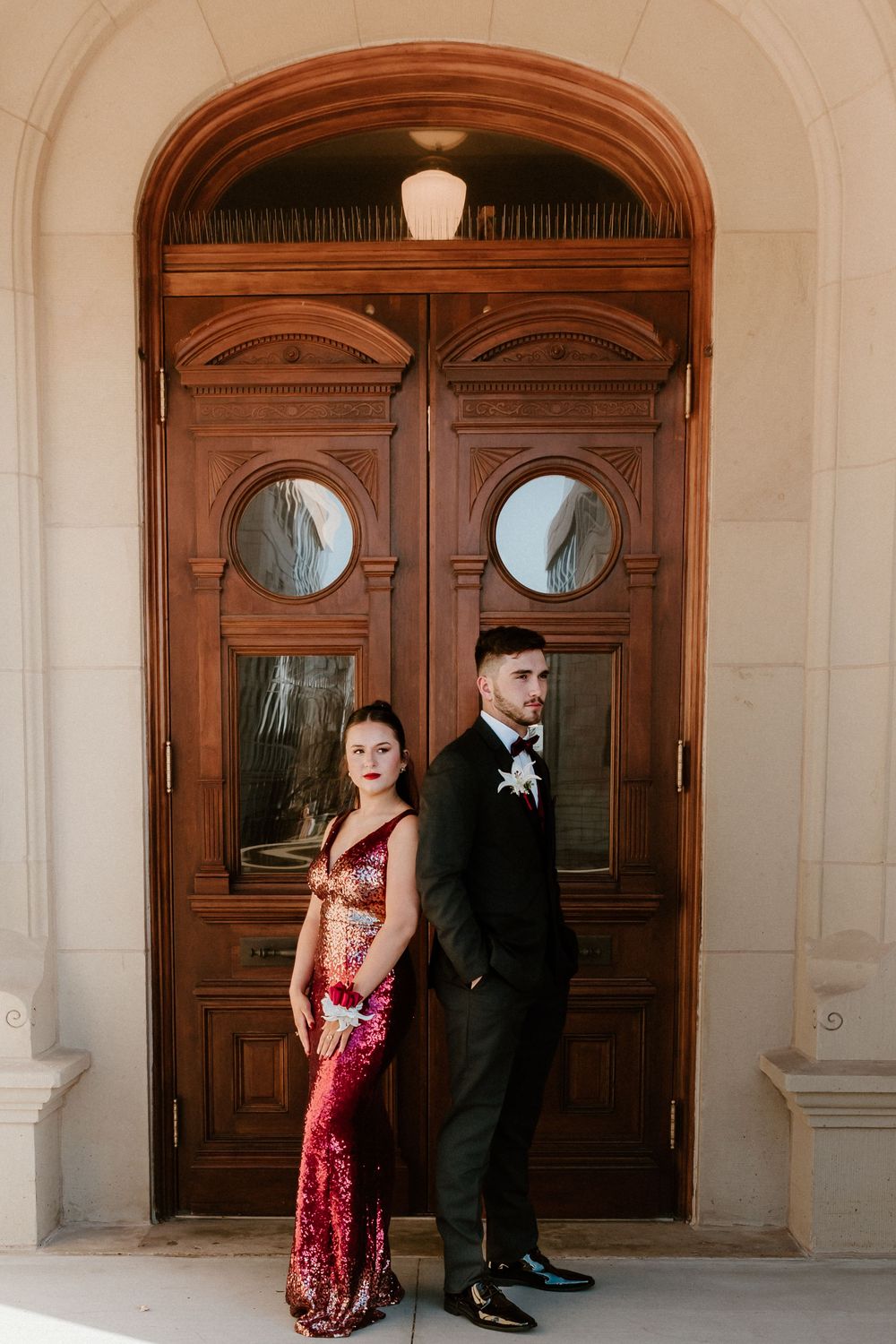 Formal portrait session in front of ornate wooden doors with arched architecture.
