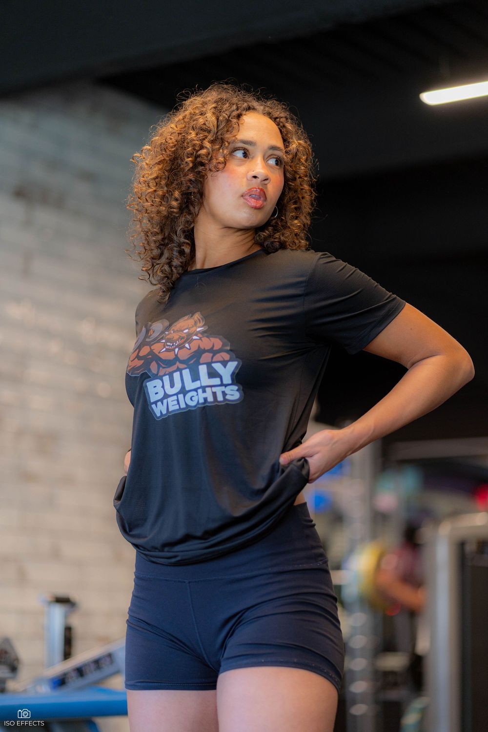 Athletic person wearing a navy blue t-shirt with a logo design and navy athletic shorts in a gym setting.