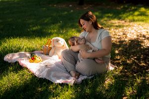 Someone enjoying a picnic on a blanket in a sunlit garden with a warm glowing lamp and small companion.