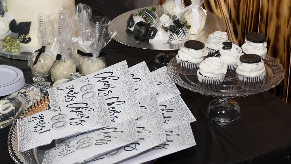 Elegant wedding or party setup with handwritten place cards and white frosted cupcakes displayed on a crystal cake stand.