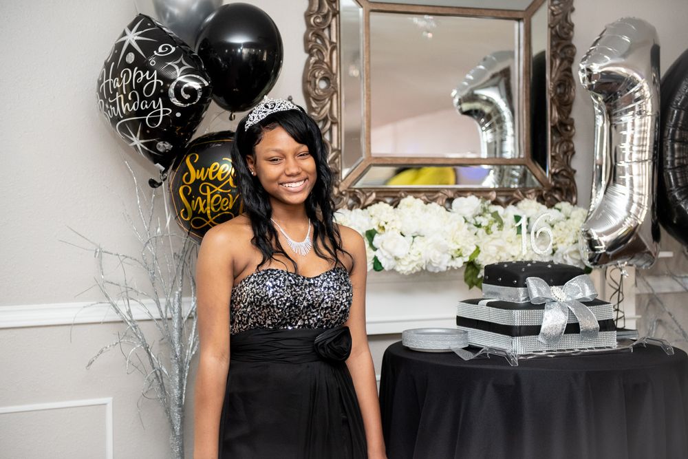 A festive party scene with black and silver balloons, elegant decor, and white floral arrangements on a table.