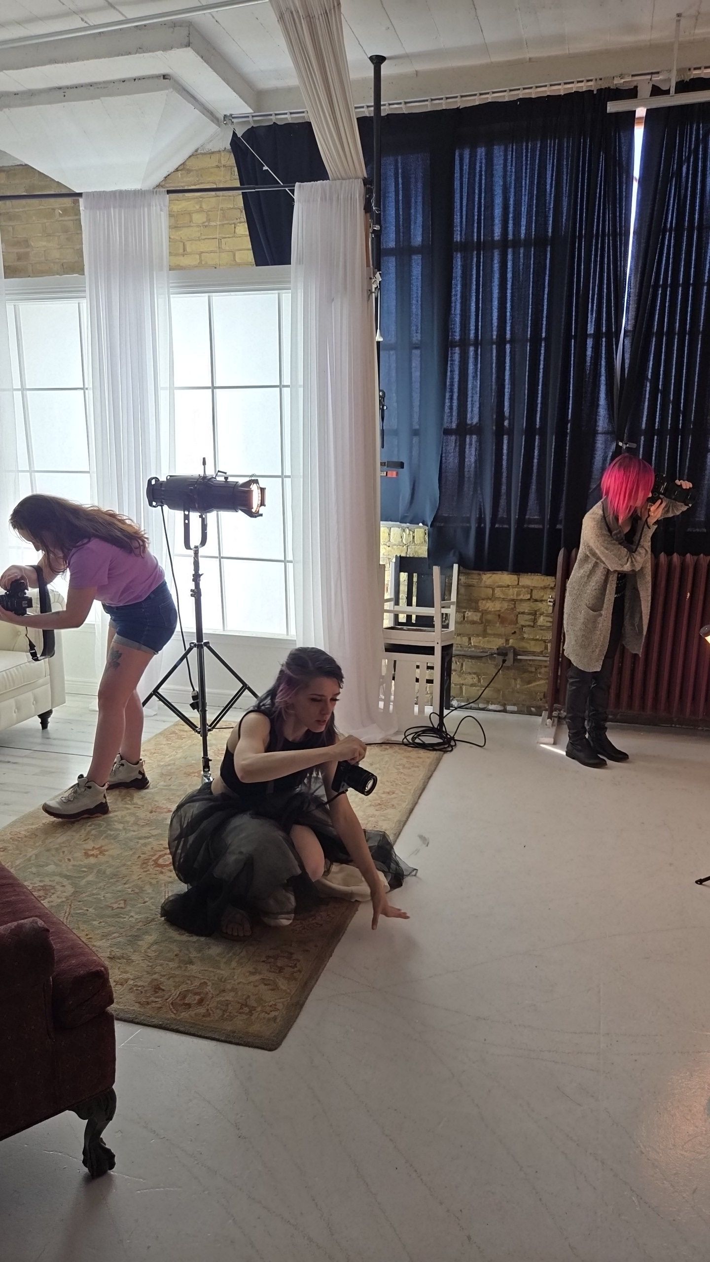 Professional photo shoot setup in a studio with lighting equipment and multiple photographers working on a fashion session.