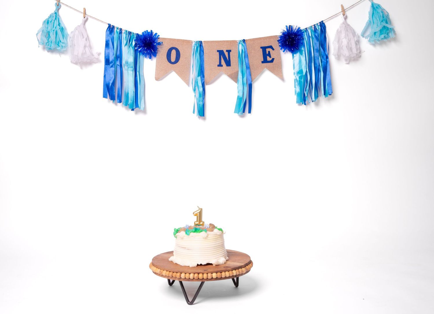 Blue and pink party decorations with 'ONE' banner hanging on white background.