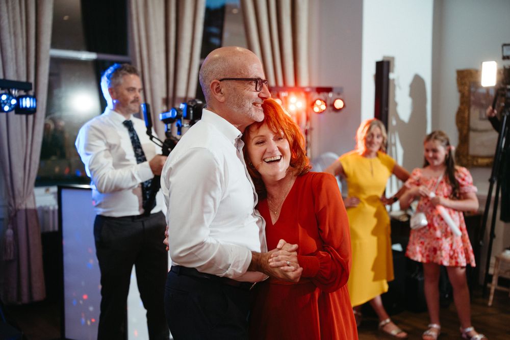 Wedding guests dancing and celebrating on the reception dance floor.