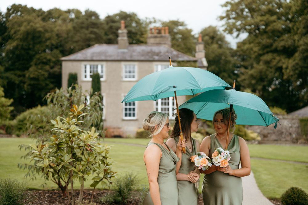 Outdoor wedding venue with green umbrellas and stone buildings in the background.