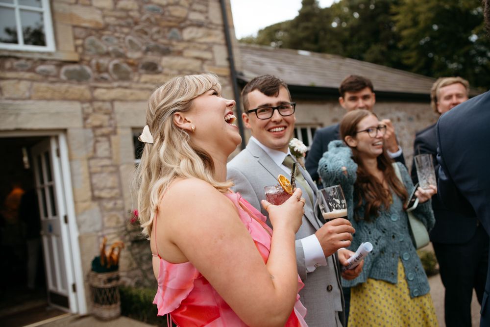 Wedding guests enjoying drinks and conversation during outdoor reception.