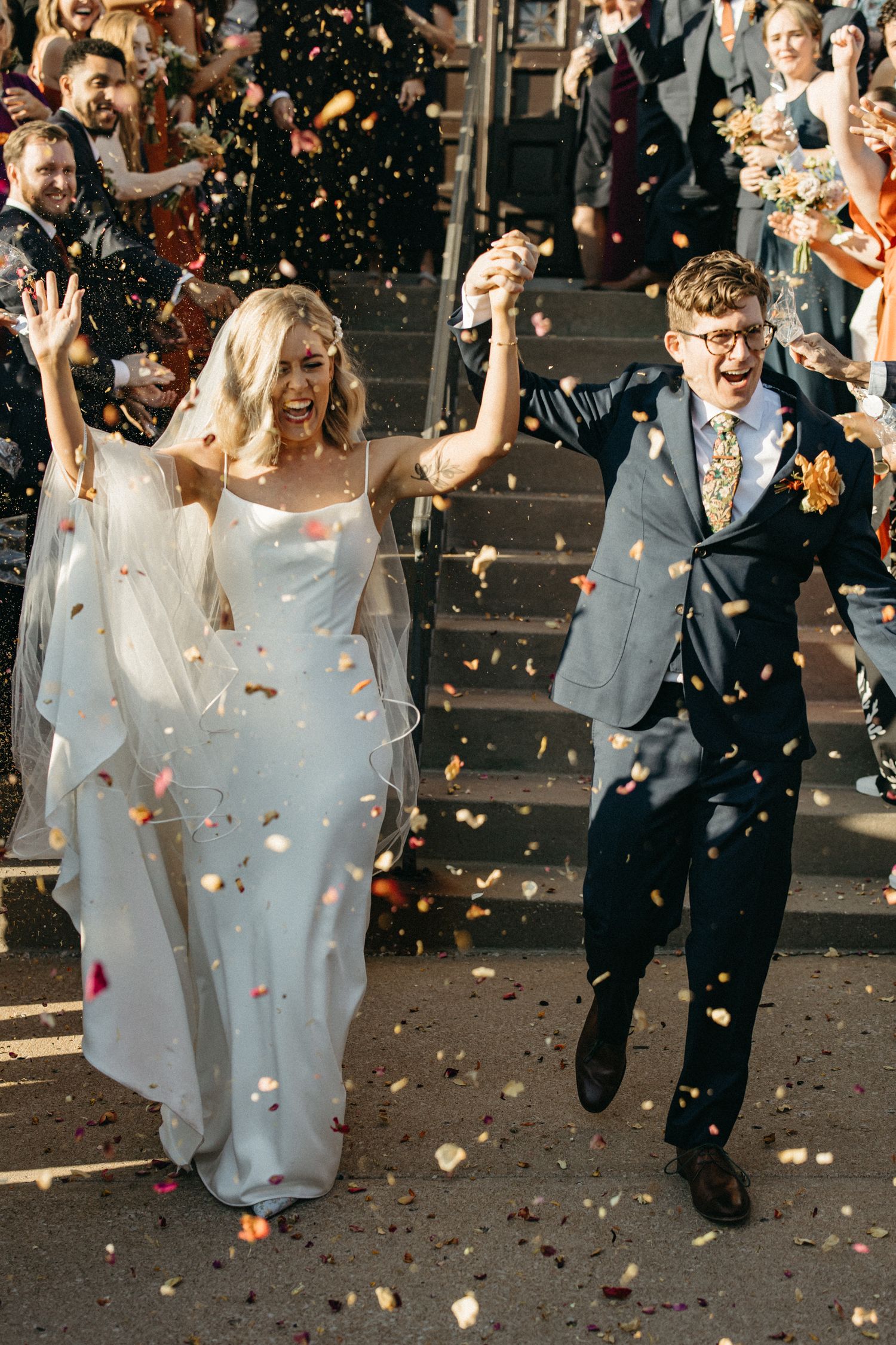 Aerial view of newlyweds walking past historic brick buildings on a city street.