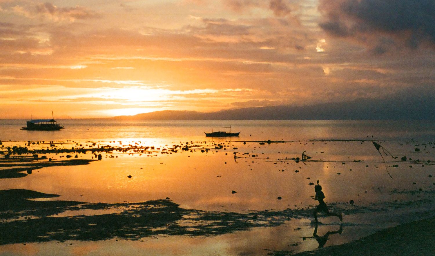 Dramatic golden sunset over water with clouds reflecting vibrant orange light.