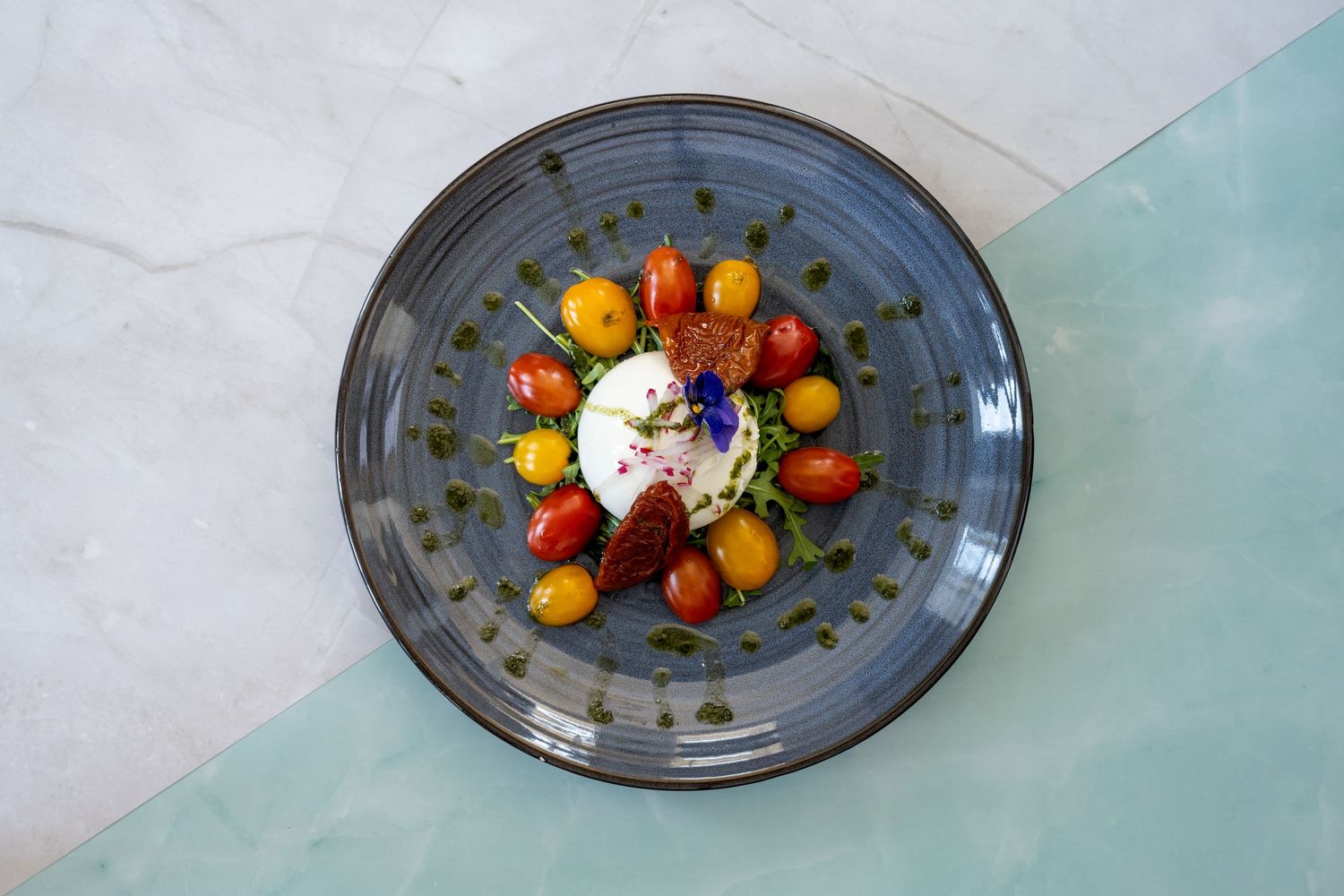 Colorful food plating progression showing ingredients being arranged on gray plates with garnishes.