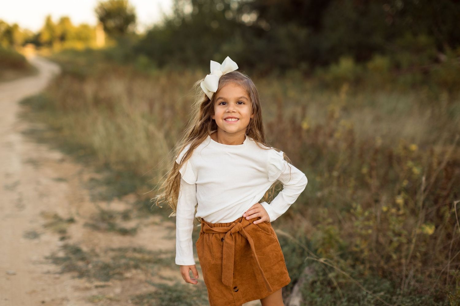 Young child in white top and brown corduroy outfit exploring outdoor setting.
