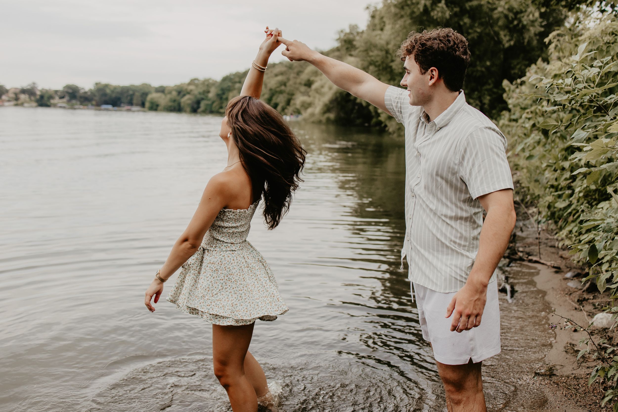 A couple dances together at the edge of a serene lake on a summer day.