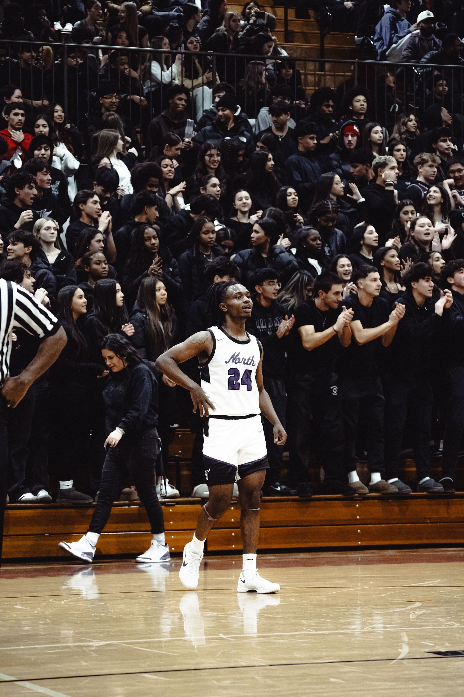 Basketball player in number 24 jersey stands on court in front of packed crowd section during game.
