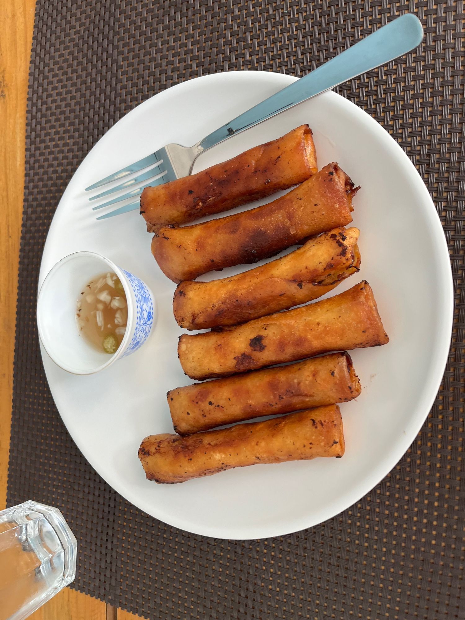 Crispy golden brown spring rolls served on white plates with utensils.