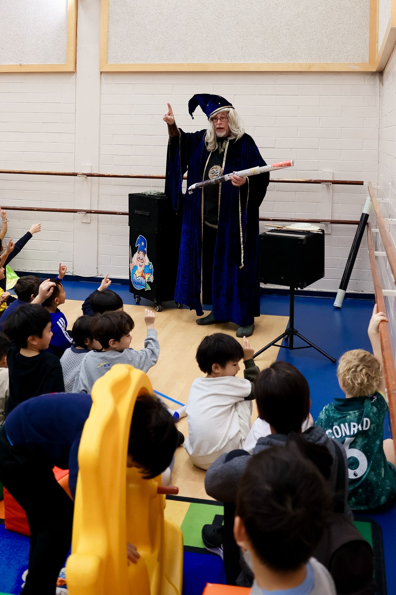 A magician addresses a group of kids setting during a birthday party.Event and Birthday Photography by Smilein.