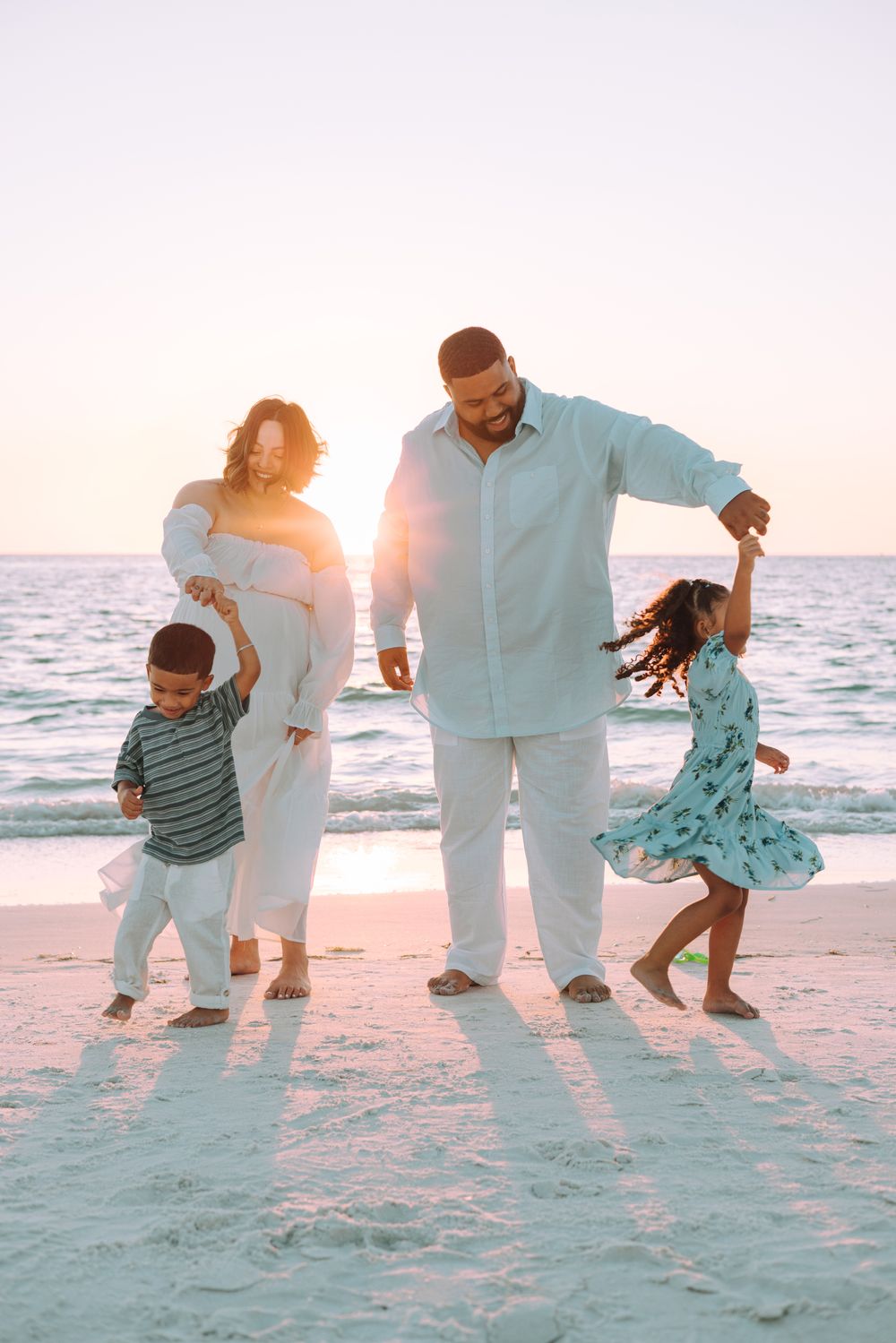 A family dances together on a white sandy beach at sunset creating a playful sequence of movement photos.