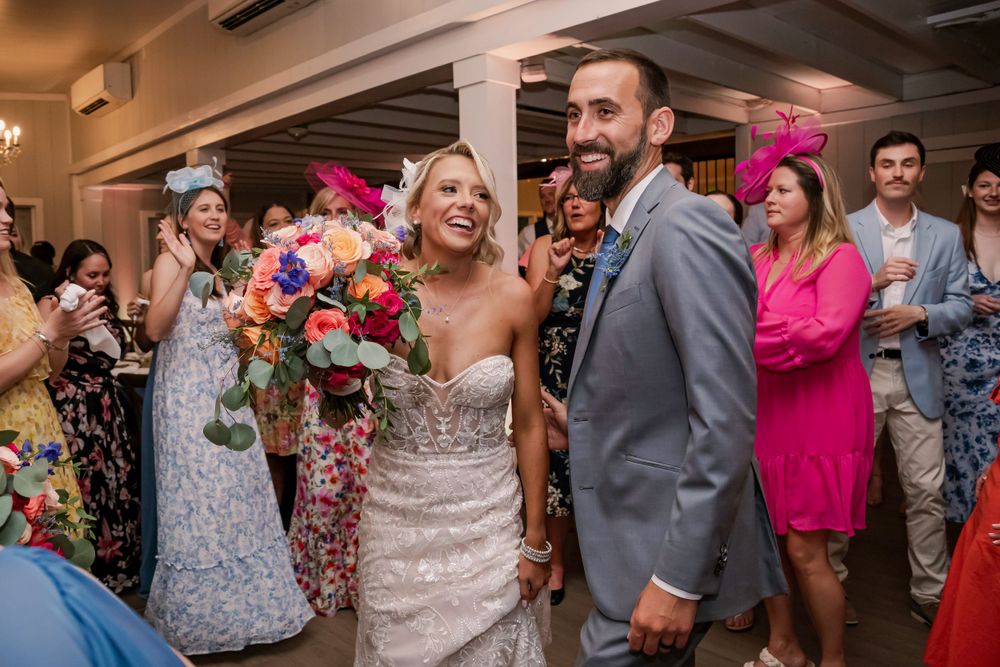 Wedding celebration with colorful bouquet and guests cheering in an indoor reception venue.