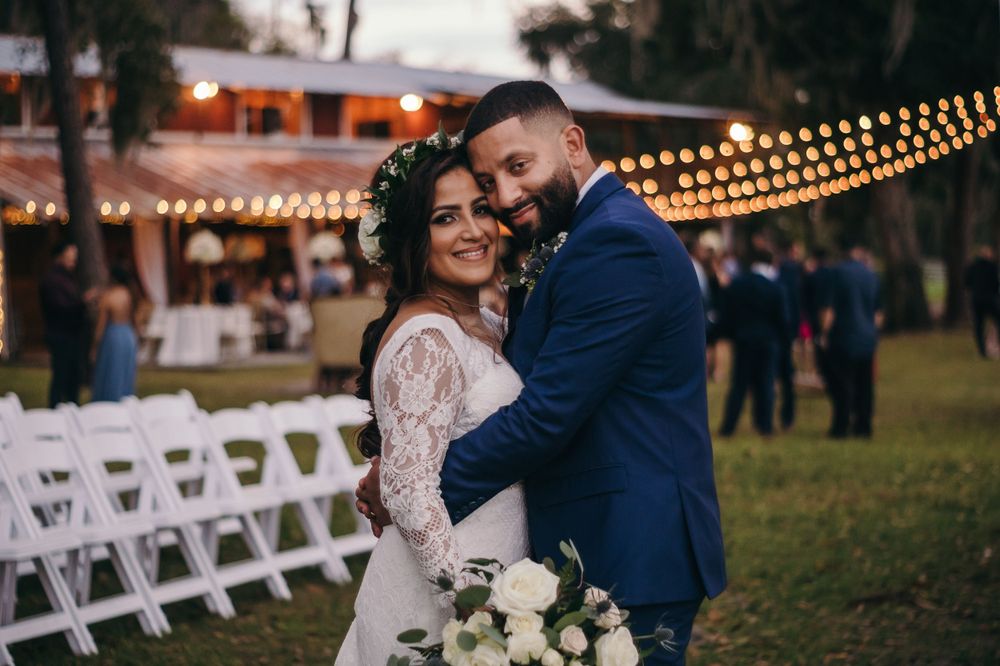 Newlyweds embrace during their outdoor evening reception with string lights overhead.