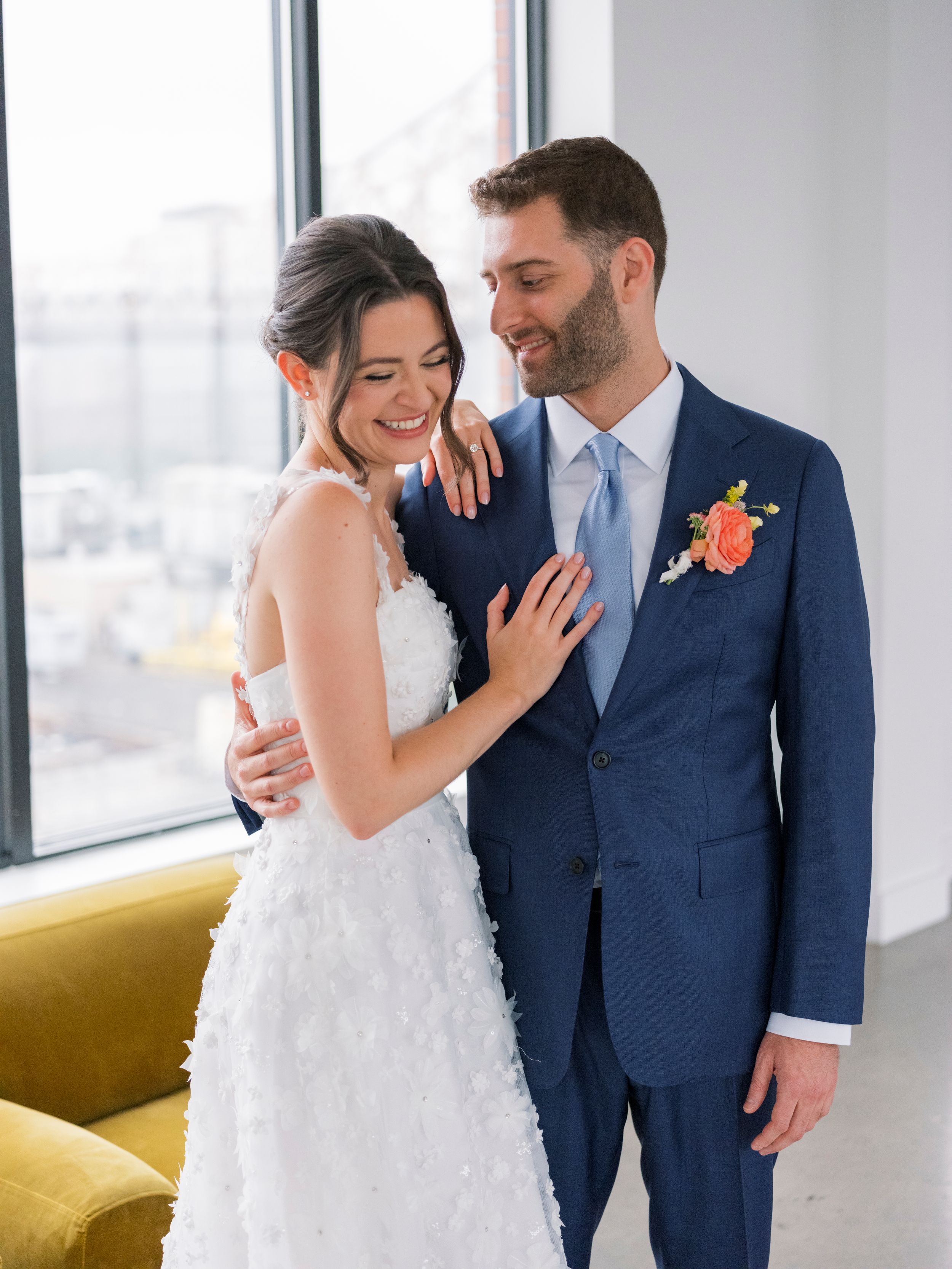 Newlyweds share intimate moments in a modern venue with bright windows and yellow accent furniture.