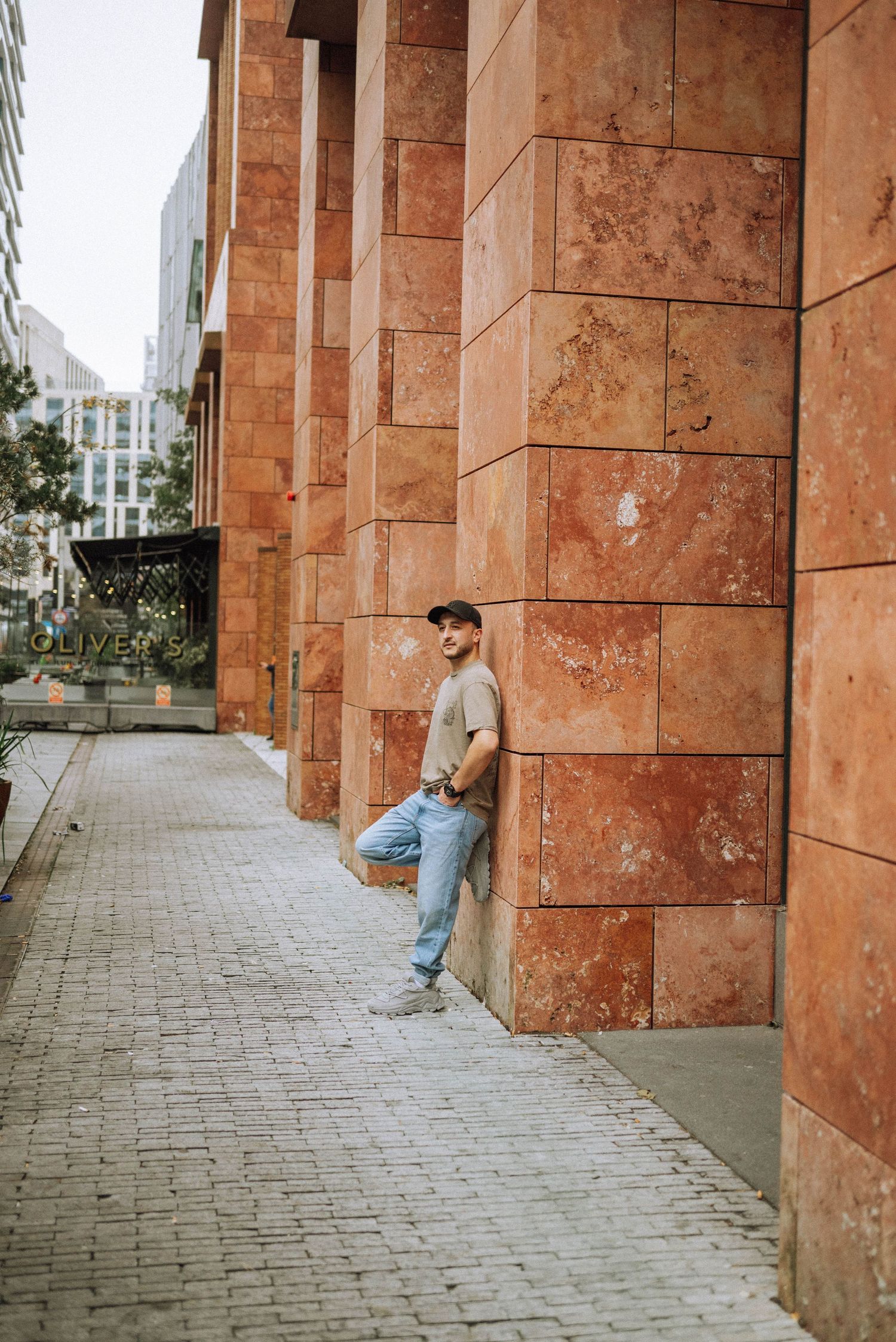 Man posing for a photoshoot in the Zuid district of Amsterdam, with modern architecture in the background.