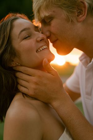 Romantic couple sharing intimate kisses against a warm sunset backdrop.
