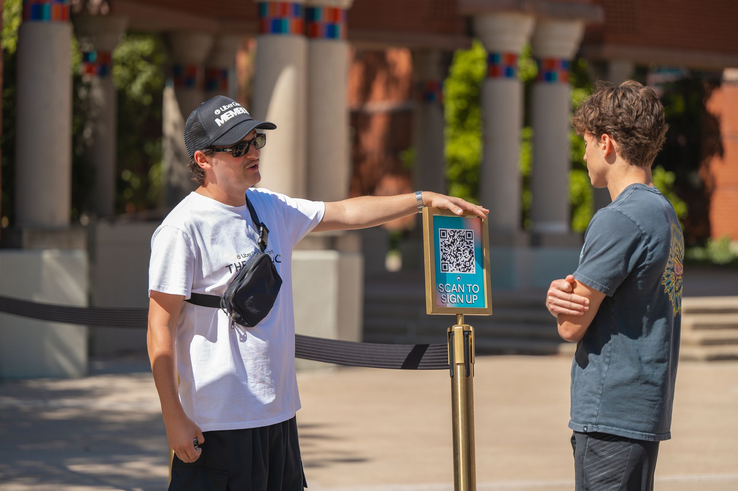 Two people interacting near an informational sign outdoors.