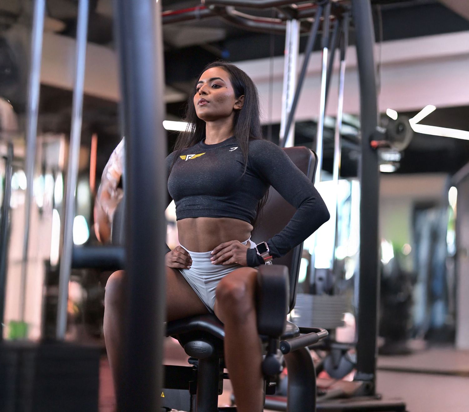 Athletic person in workout attire takes a break between sets at a modern fitness gym.