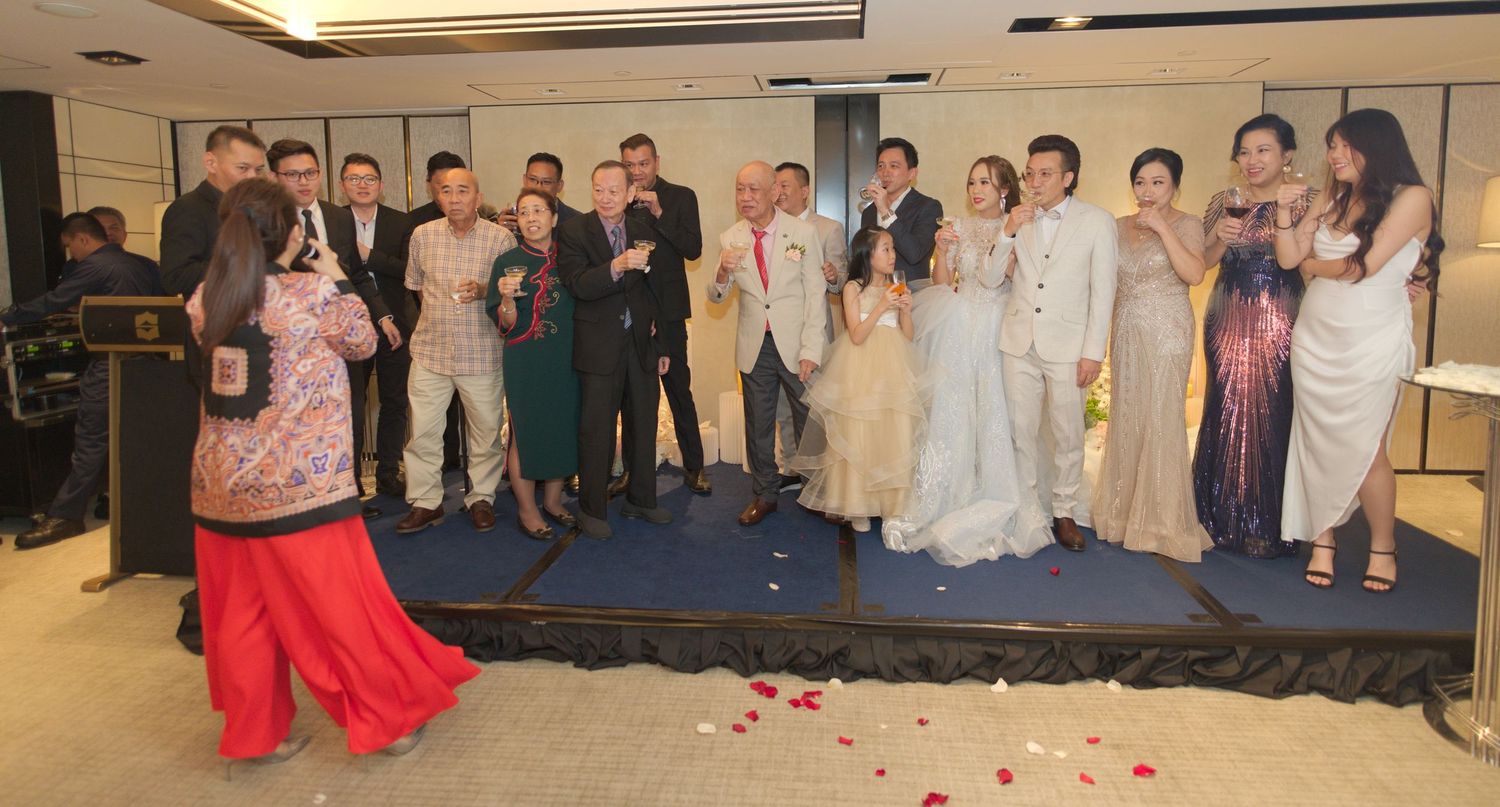 Wedding party members gathered on a blue stage for a group photo during the reception.