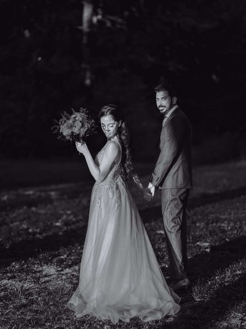 Dramatic black and white nighttime wedding portraits in a garden setting.
