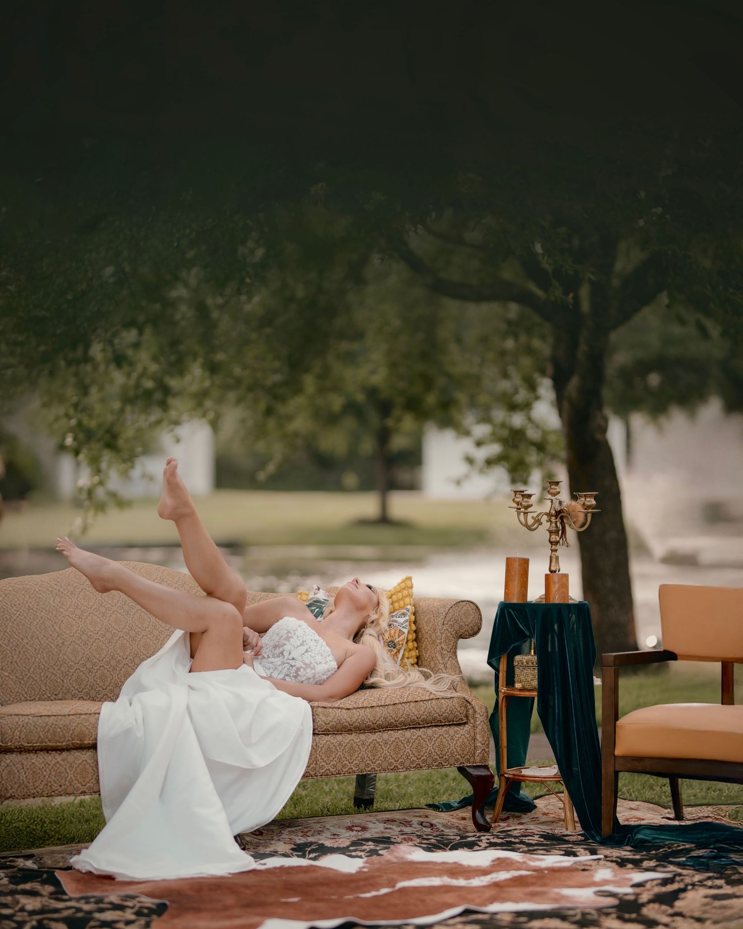 Artistic wedding photo with couple lounging on outdoor furniture at dusk.