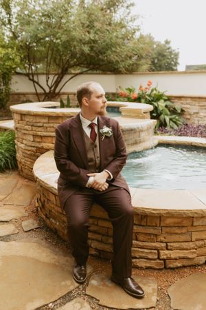 Groom portrait in brown suit by fountain Fort Worth TX, vintage storytelling wedding photography.