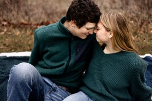 Intimate couple in matching green sweaters share a tender moment outdoors.