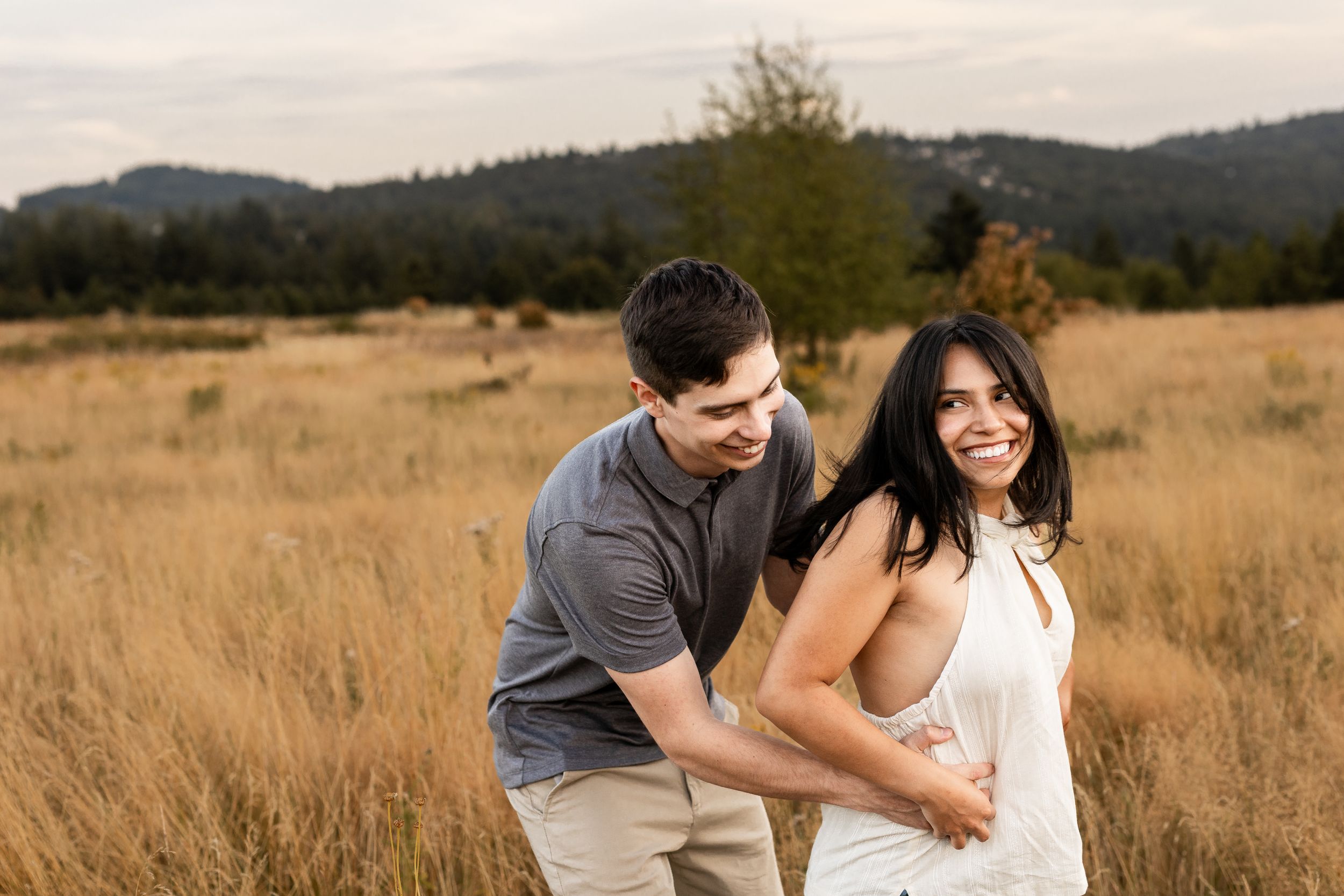 A couple shares tender moments together in a golden autumn field at sunset.